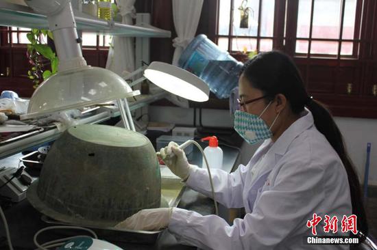 修复师采用机械方法对青铜器表面的锈蚀进行清除  徐雪 摄