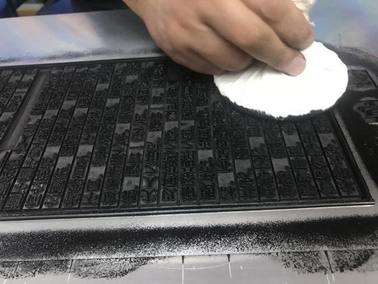 上海字模一厂副厂长刘现云演示拓印铅活字排版的《兰亭序》。