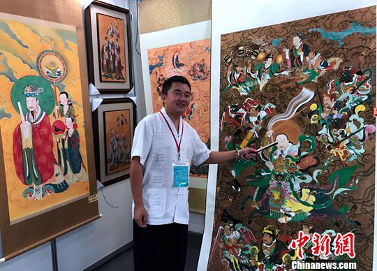 图为上海绘真堂总经理王琛介绍他带来的传统重彩工笔道教神像画。中新社记者 邢利宇 摄
