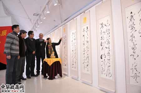 图为杨希仁(右二)与前来参观的书法爱好者一同观看玉雕“圣土望君归”和<望君归礼赞>书法狂草书法作品。