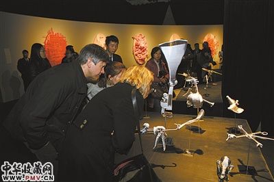 展览现场，观众观看林天苗用丝线、金箔等缠绕创作出的骨骼、金属工具等作品。