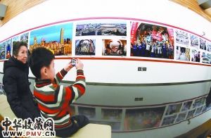 图为一名小观众在美丽北京――“北京精神”群众摄影文化活动优秀作品展上拍摄展览作品。 本报记者 贾同军摄
