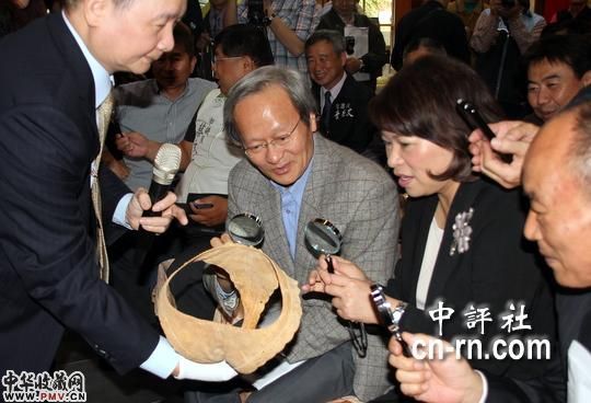 嘉义市长黄敏惠等人拿起放大镜，欣赏这件薄如蝉翼、可透光的木雕内裤“行走的女人”。(嘉义市政府提供)