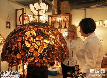 3月10日，两名琥珀经销商在波兰格但斯克举行的国际琥珀节上展示琥珀灯。新华网图片 高帆 摄