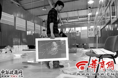 昨日,工作人员拿着方力钧的作品正在布展 本报记者 闫文青 摄