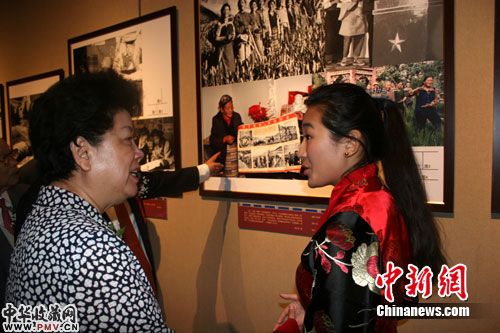 图为中国传媒大学藏族女大学生丹增敏吉为陈至立讲述参展图片背景。肖媛媛 摄