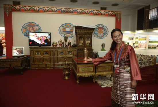 6月15日，工作人员边巴卓玛在“阿努一家的幸福生活场景”展区邀请参观者参观。