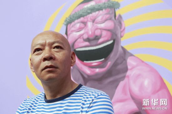 6月15日，在北京798艺术区佩斯北京画廊，岳敏君与他创作的“笑脸”画作合影。