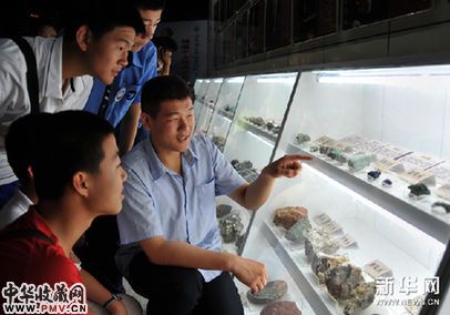 杨溢(右)向前来参观他的个人矿石收藏展的青少年介绍展品。新华网图片 徐速绘 摄