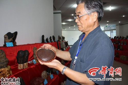 市奇石协会会长冯忠贤拿着收藏的心形石头向市民展示。