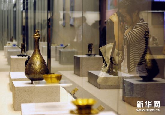 一位参展者正在拍摄展出的金银器。