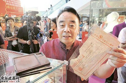 著名“红色收藏家”金铁华在会场向参观者解释藏品，包括一套毛泽东曾经在1949年进驻北京后使用的毛笔和砚台（左），和一份中华人民共和国开国大典的邀请函（右）。（香港明报图 叶汉华摄）