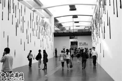 刘建华装置艺术《啸墙》,作者制作了200多件黑色的陶瓷制品,并固定在白色的墙壁上。