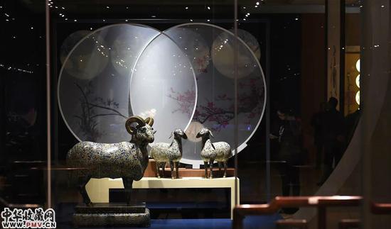 12月25日，观众在“三阳开泰”展位上陈列的文物旁参观。