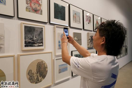 参展艺术家王劲松在艺术家作品墙前